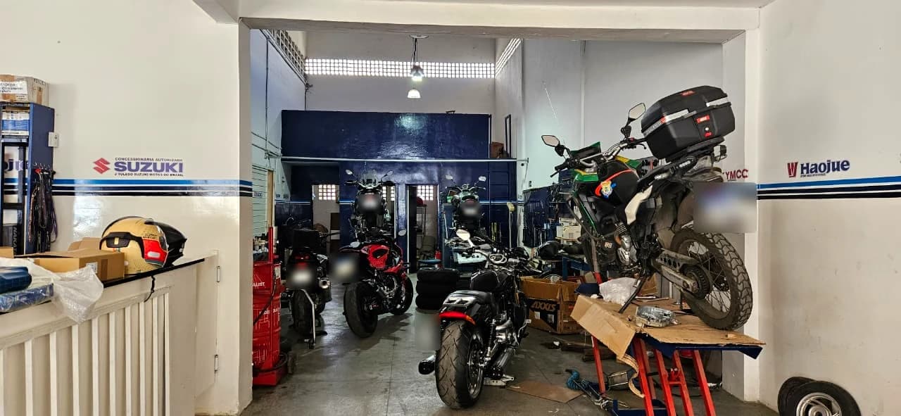 Oficina da Suzuki Urbanu's, com motos em manutenção e as marcas Suzuki e Haojue na parede