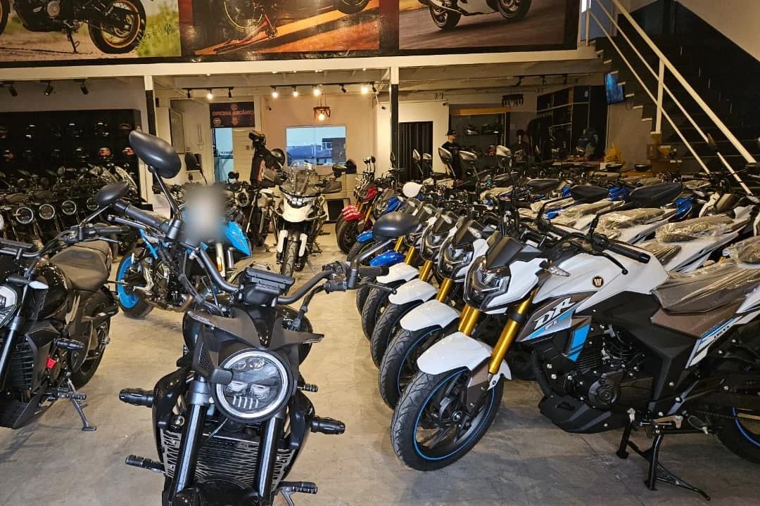 Showroom da Suzuki Urbanu's cheio de motos enfileiradas, com capacetes e acessórios ao fundo